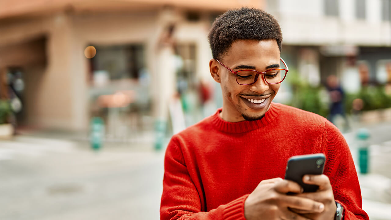 Man on his smartphone logging in, wearing a red sweater