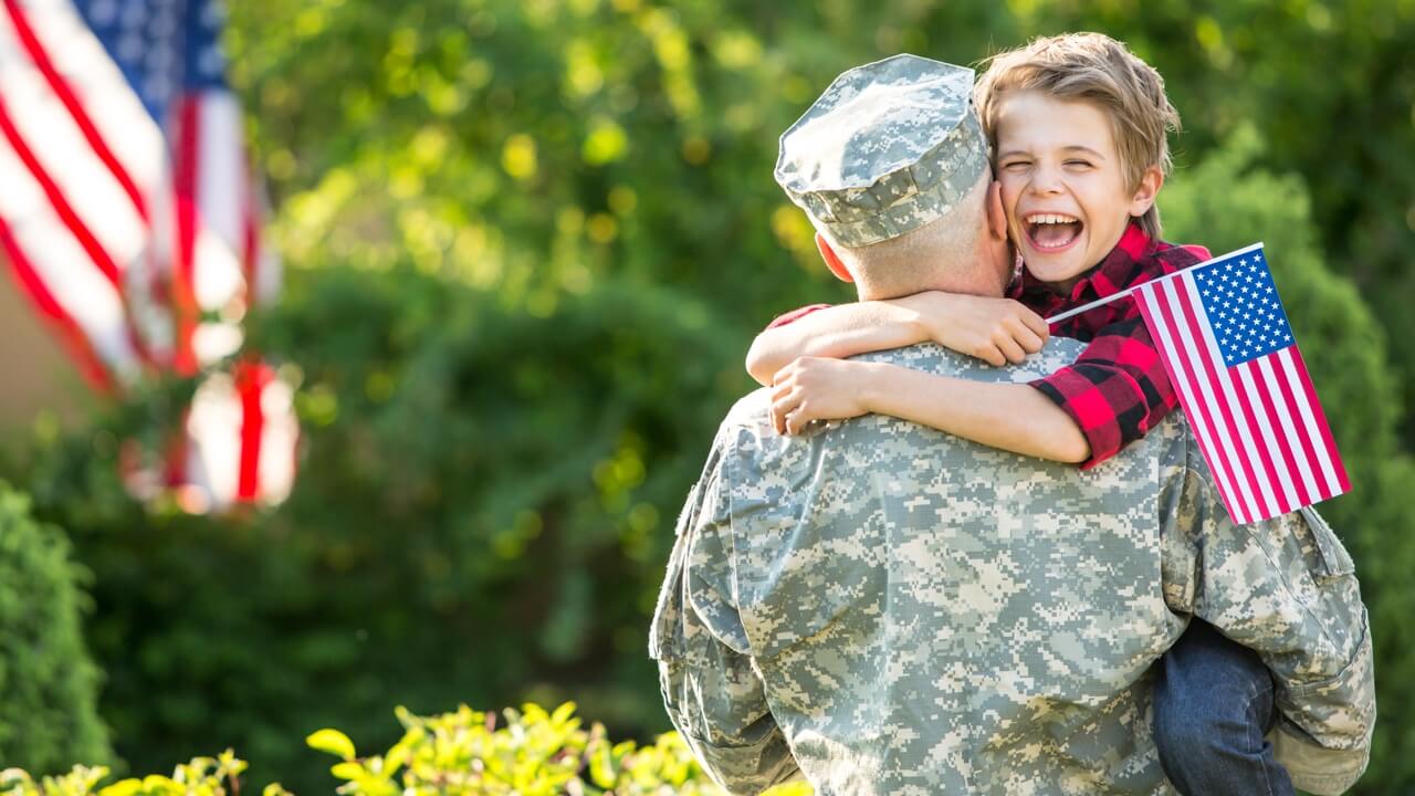 Soldier hugging son holding a small flag