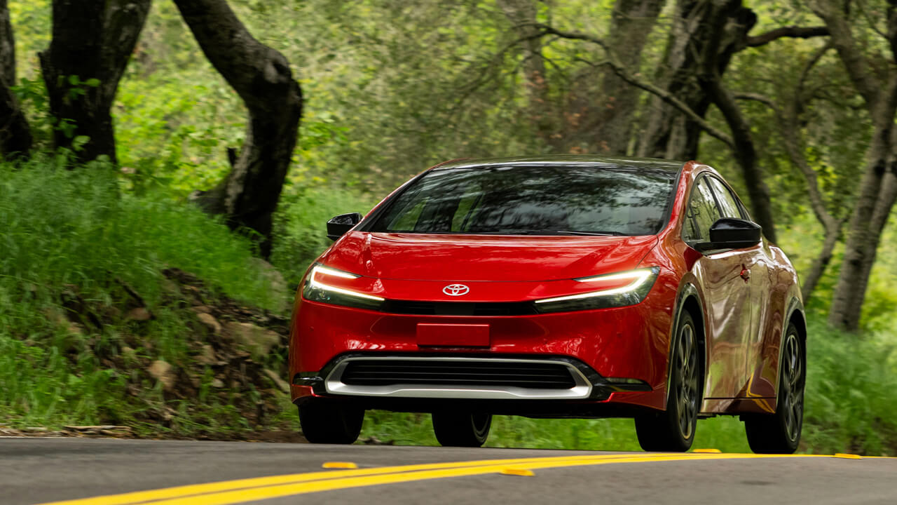 Red 2024 Prius driving in the countryside