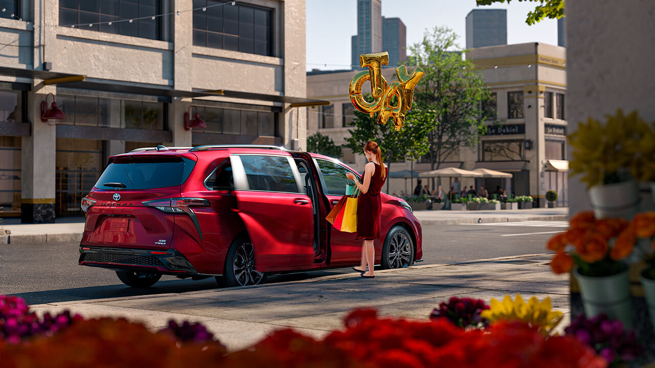 Woman getting into her red 2022 Toyota Sienna with balloons that spell "Toyota"