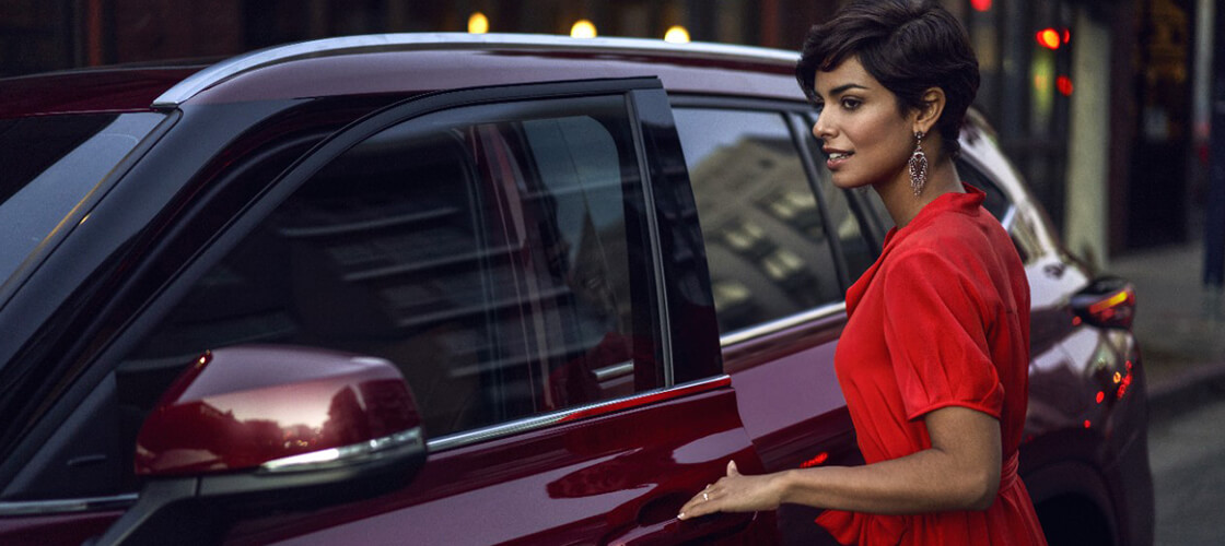 Woman getting into her maroon Highlander Hybrid