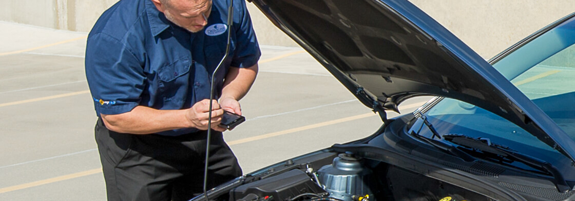 An inspector peeks under the hood of a vehicle. 