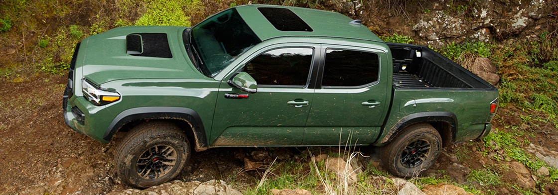 A green Tacoma TRD Pro drives up a rocky incline. 