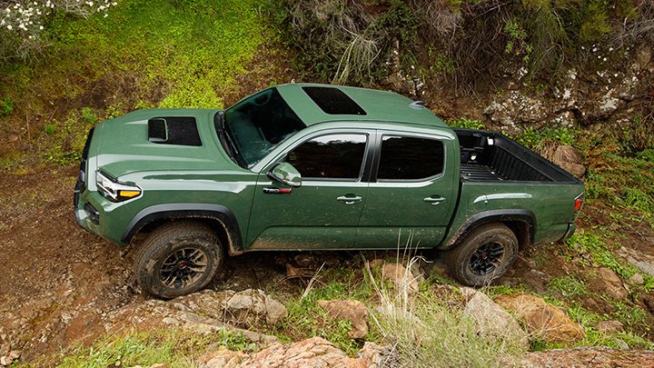 A green Tacoma TRD Pro drives up a rocky incline. 