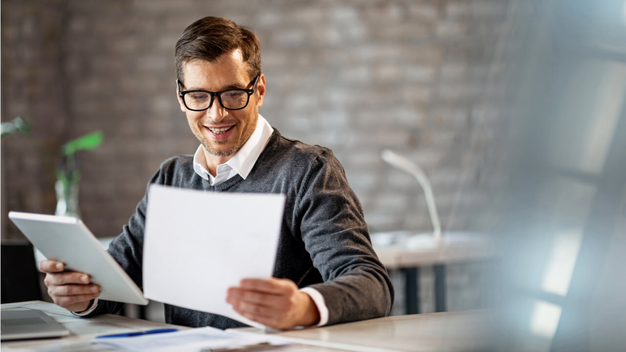 Man reviewing paperwork and his tablet