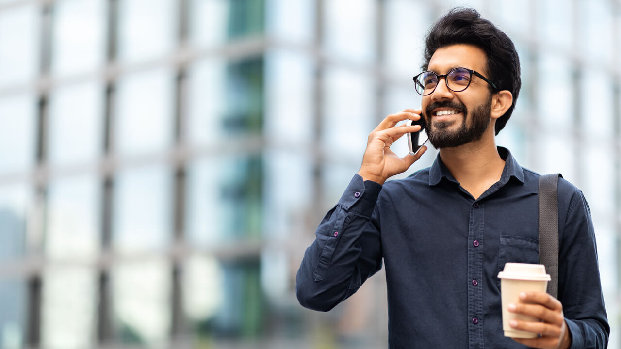 Man talking on the phone outside, holding a coffee cup