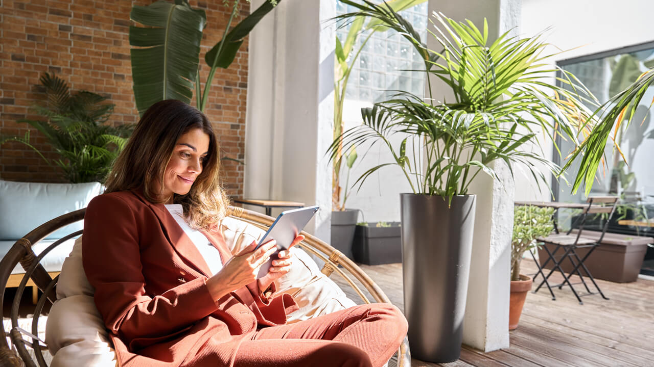 Woman browsing tablet while sitting in sunshine in her chair